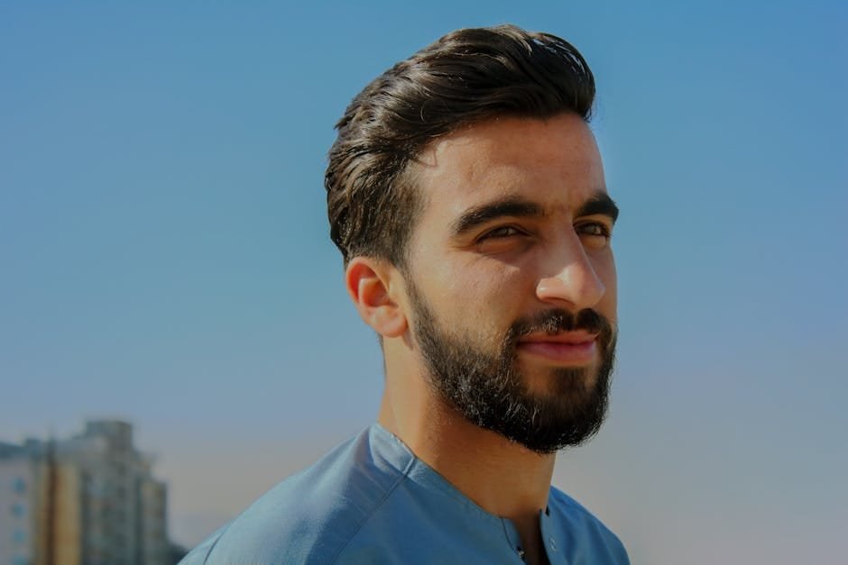 pexels-photo-819530-819530 | CyberGuardian A close-up outdoor portrait of a young man with facial hair, exuding confidence under a clear sky.